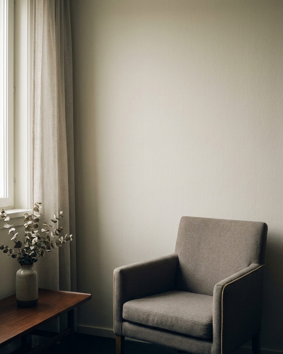 A quiet room with soft daylight through a window and an empty armchair